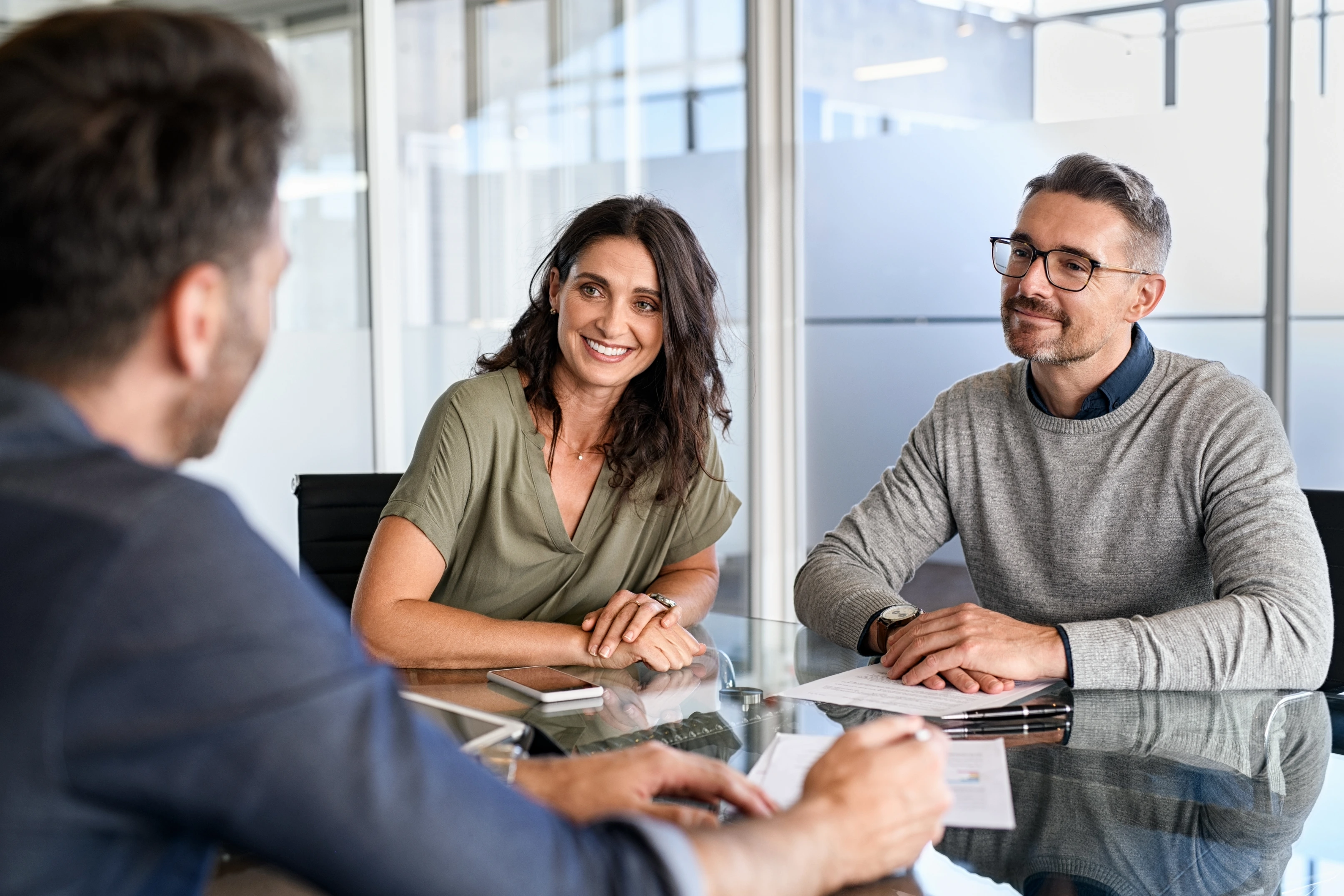 Drei Personen sitzen an einem Tisch in einem Büro